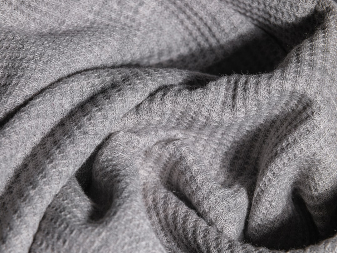 Close-up of a pilled grey sweater fabric before treatment